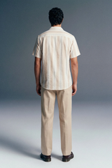 Man wearing a striped shirt and beige pants against a gray background