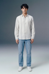 Person wearing a white striped shirt and blue jeans against a gray background