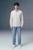 Person wearing a white striped shirt and blue jeans against a gray background