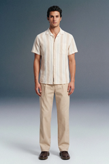 Man wearing a striped shirt and beige pants against a plain background