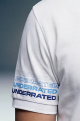 A close-up shot of the short sleeve of a white polo shirt, focusing on the cuff details. The cuff features the word 