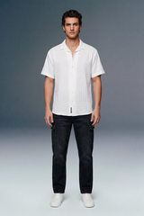 Man wearing a white shirt and black pants on a gray background