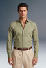 Man wearing a green shirt and beige pants against a gray background