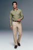 Man wearing a green shirt and beige pants on a gray background