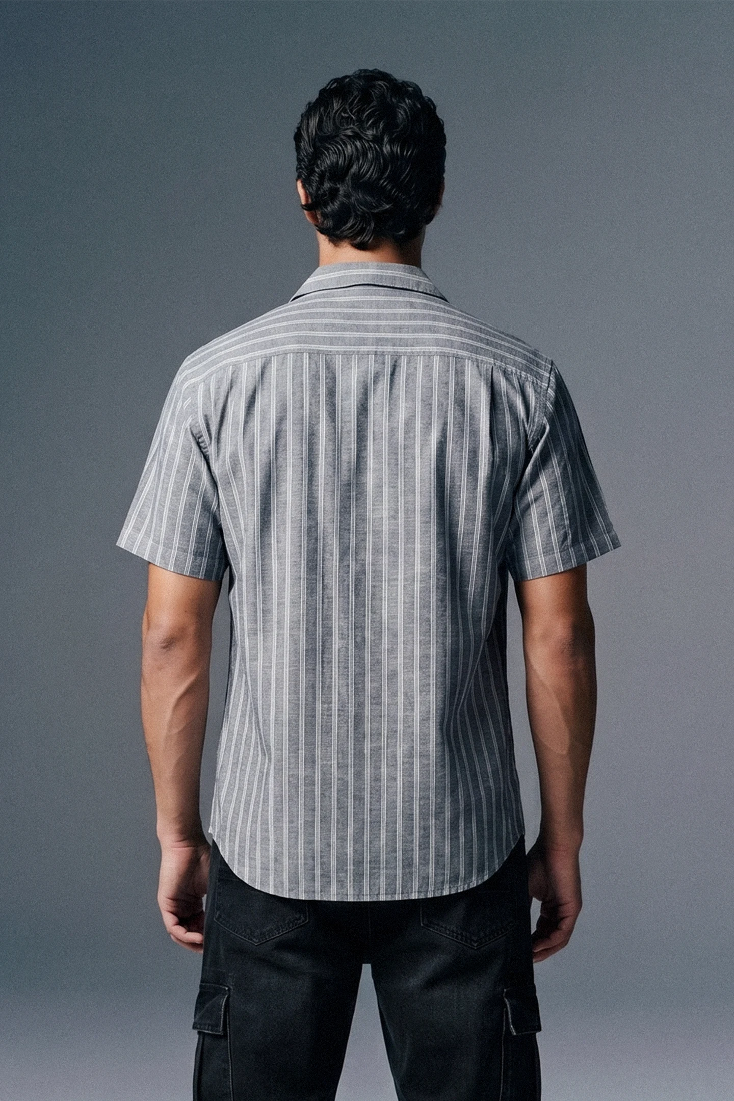 Man wearing a striped shirt from behind on a gray background