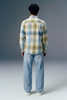 Person wearing a plaid shirt and jeans from behind on a gray background