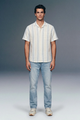 Man wearing a striped shirt and jeans against a plain background