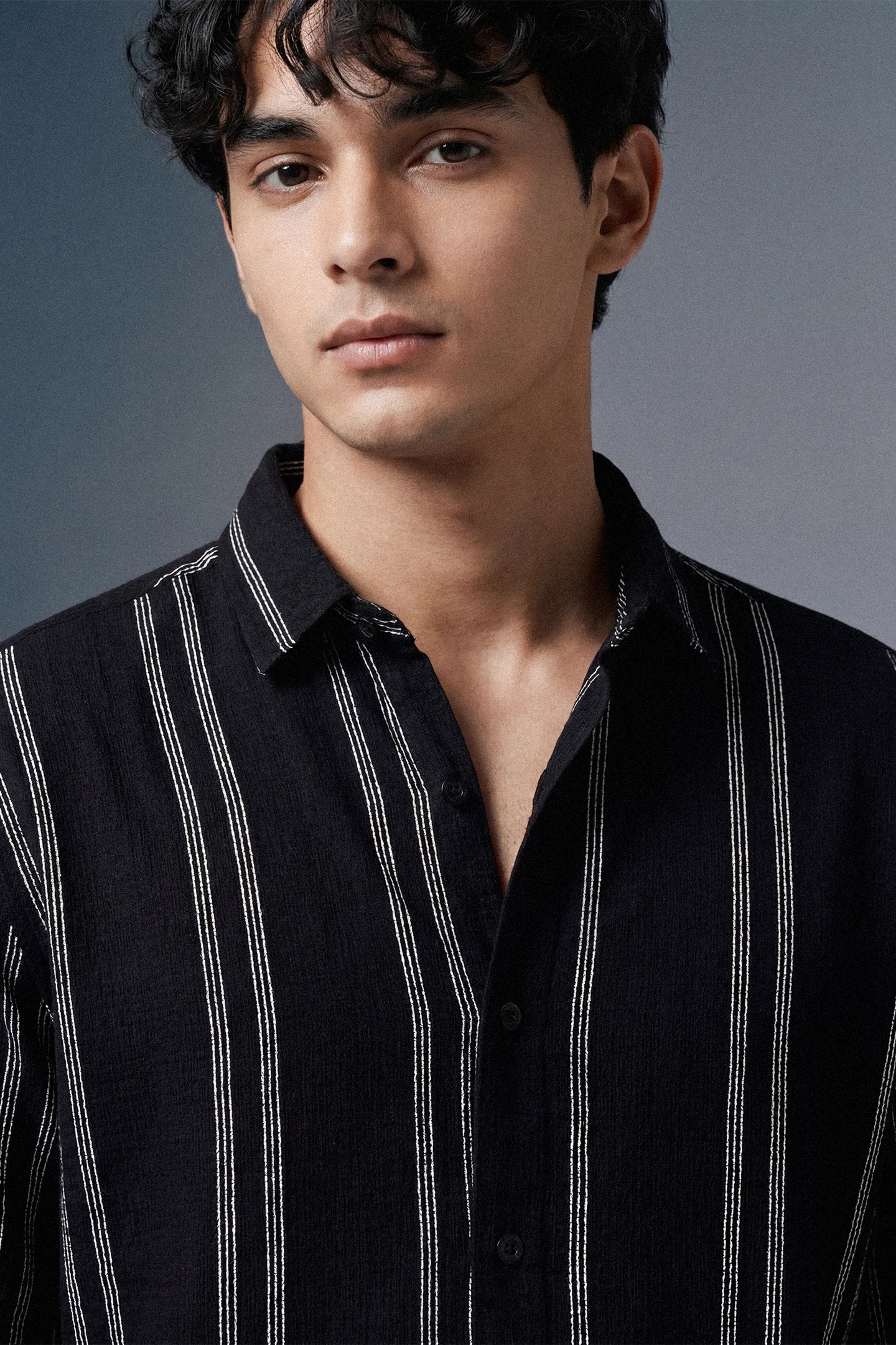 Man wearing a black striped shirt against a gray background