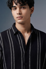 Man wearing a black striped shirt against a gray background