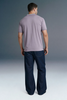 Full-length rear view of a man standing straight, showing the back profile of a light purple polo shirt and dark navy blue trousers.
