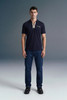 Front view from the waist up of a man looking forward, wearing a navy blue polo shirt with a contrasting beige or checkered inner placket and collar detailing.