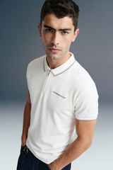A close-up, high-angle front view of a man wearing an off-white polo shirt, showcasing a thin contrast stripe along the collar edge and subtle branding on the left chest.