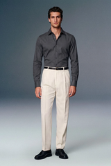 Man wearing a gray shirt and beige pants against a plain background