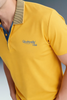 Side profile close-up focusing on the shoulder and collar of a mustard yellow polo shirt, showing a khaki knit collar texture and blue graphic branding on the left chest.
