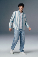 Man wearing a striped shirt and jeans on a gray background