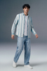 Man wearing a striped shirt and jeans on a gray background