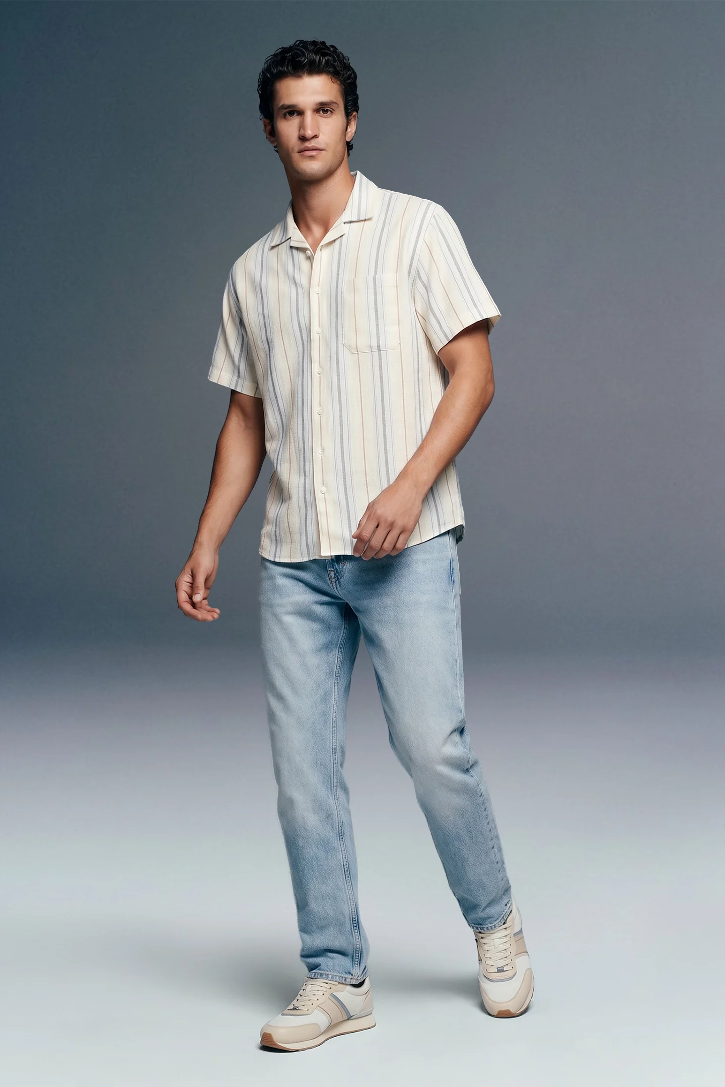 Man wearing a striped shirt and jeans on a gray background