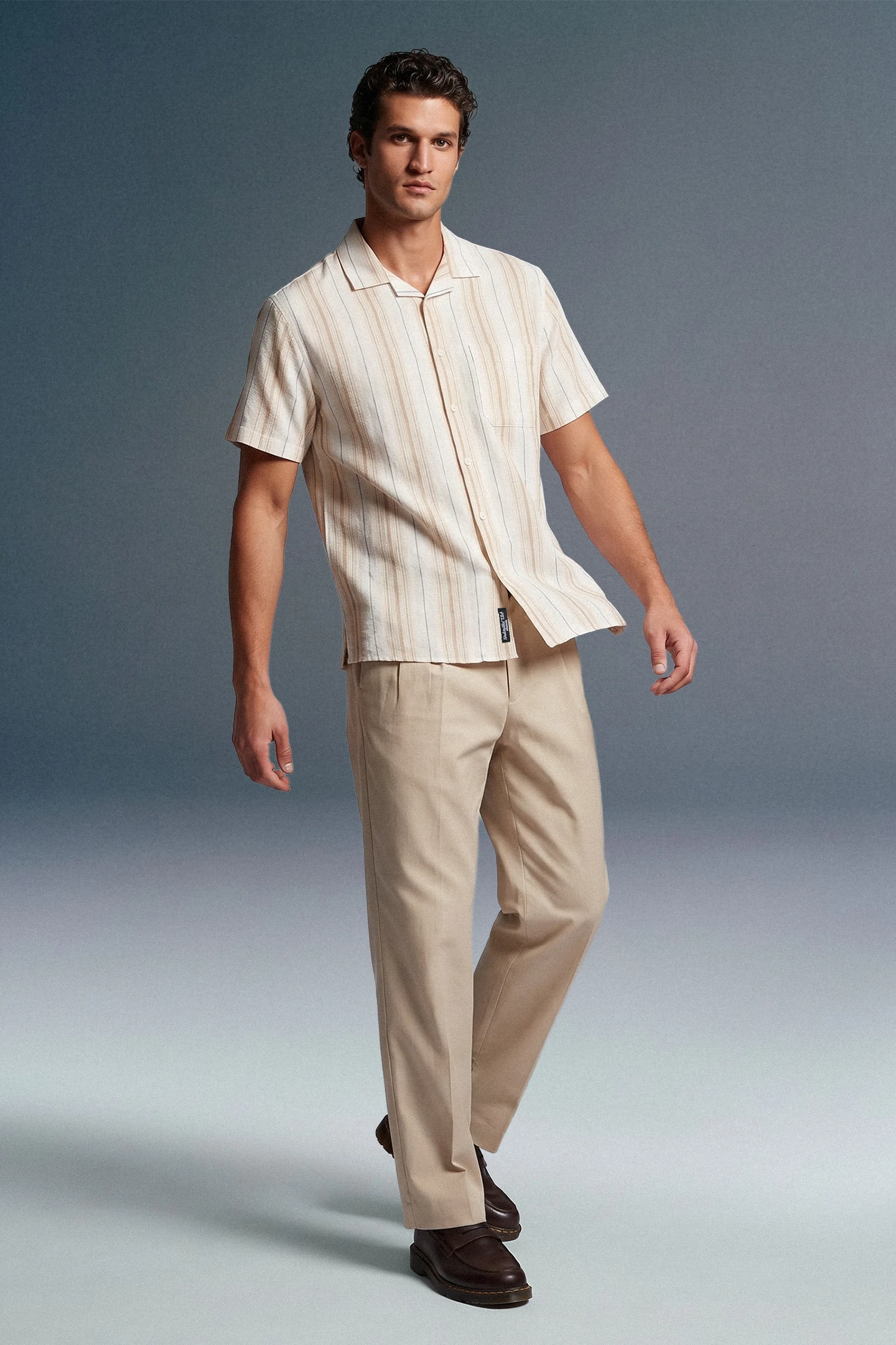 Man wearing a beige striped shirt and pants on a gray background