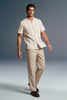 Man wearing a beige striped shirt and pants on a gray background