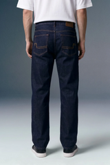 Person wearing dark blue jeans with a plain background
