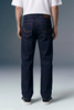 Person wearing dark blue jeans with a plain background