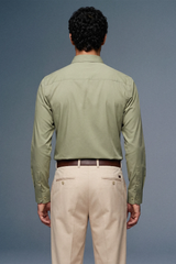 Man wearing a light green shirt and beige pants against a gray background