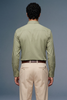 Man wearing a light green shirt and beige pants against a gray background