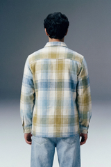 Person wearing a plaid shirt and jeans against a gradient gray background