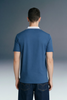 Rear view from the waist up of a man wearing a slate blue polo shirt with a contrasting white collar.