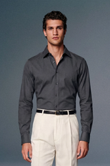 Man wearing a gray dress shirt and white pants against a plain background