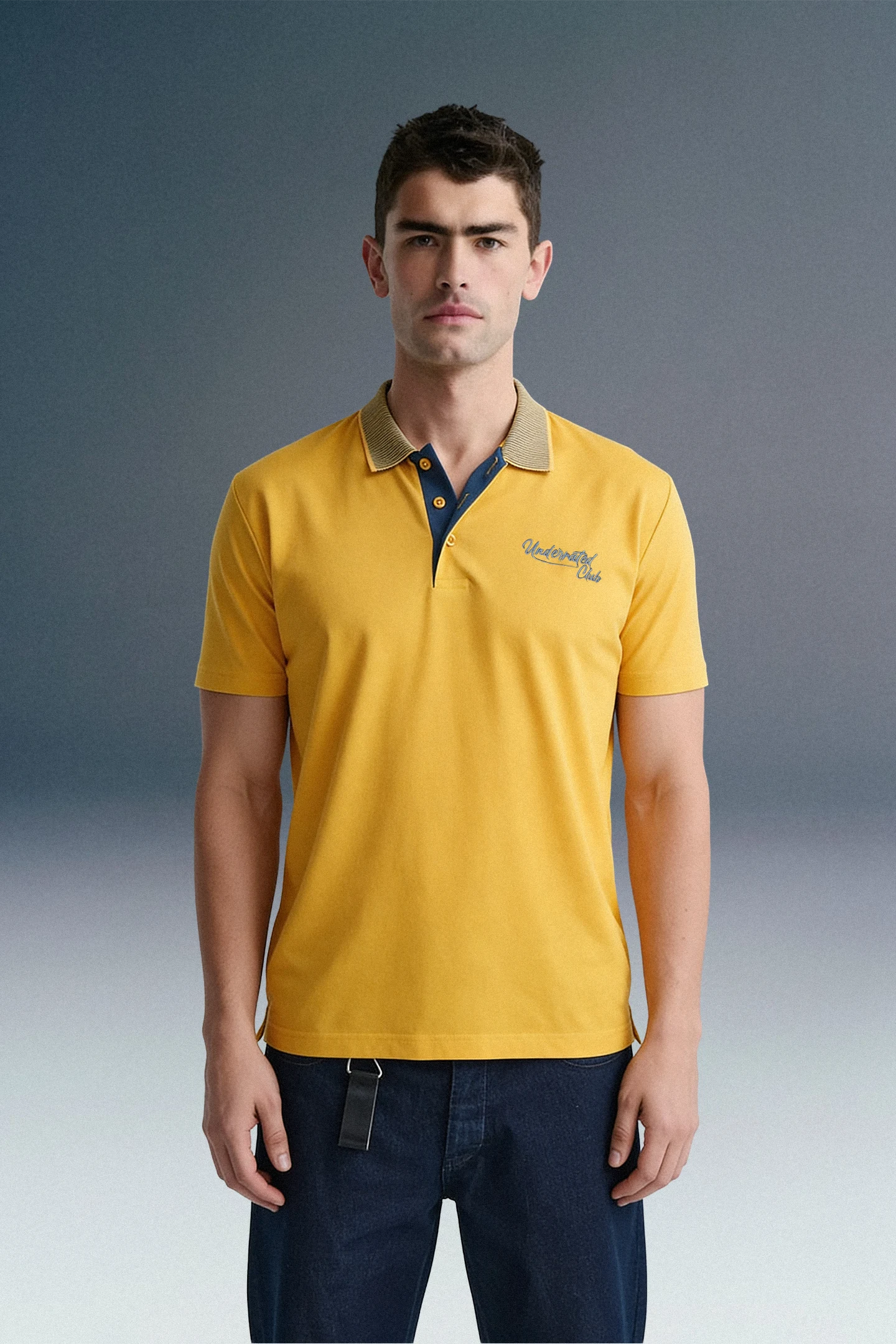 Three-quarter front shot of a man facing forward, wearing a mustard yellow polo shirt with contrasting blue-and-white patterned collar and inner placket detailing.