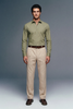 Man wearing a green shirt and beige pants against a gray background