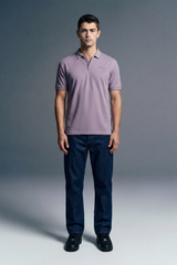 Full-length front view of a man standing still, wearing a light lavender polo shirt paired with dark blue trousers.